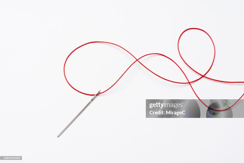 Threading a Needle With Red Curved Thread