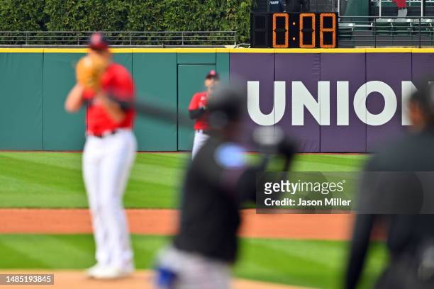 The pitch clock is seen behind starting pitcher Shane Bieber of the Cleveland Guardians a he pitches to Luis Arraez of the Miami Marlins during the...