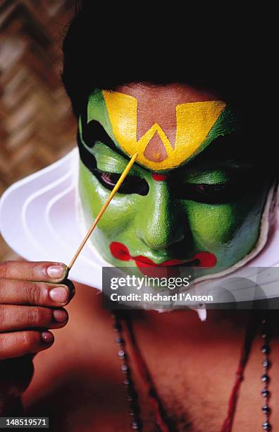 kathakali dancer applying make-up before performance. - kathakali stock pictures, royalty-free photos & images