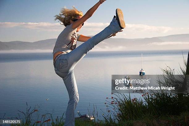 girl high-kicking with sea in background. - hög spark bildbanksfoton och bilder