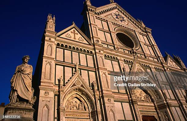 statue of dante alighieri stands beside the basilica di santa croce in florence. - basiliek stockfoto's en -beelden