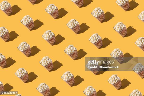 pattern of cardboard popcorn boxes with white and red decoration on yellow background. cinema, entertainment, film, show, fat, unhealthy food, fast food and fatness concept. - movie awards show stockfoto's en -beelden