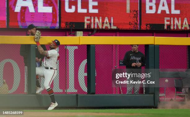 Kevin Pillar of the Atlanta Braves collides with the fence as he fails to catch this inside-the-park home run by Yuli Gurriel of the Miami Marlins in...