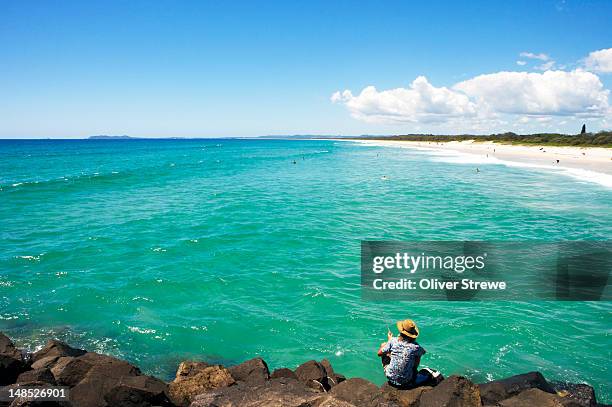 man fishing off rock groin at brunswick heads. - brunswick heads nsw stock pictures, royalty-free photos & images