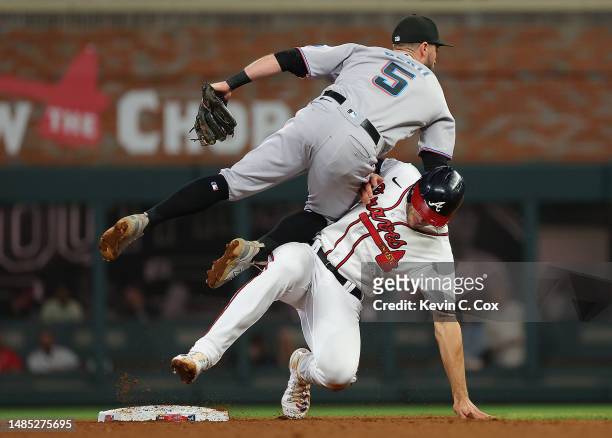 Jon Berti of the Miami Marlins collides with Matt Olson of the Atlanta Braves as he turns a double play in the seventh inning at Truist Park on April...