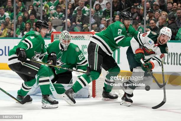 Marcus Johansson of the Minnesota Wild attempts to gain control of a loose puck in front of Jani Hakanpää of the Dallas Stars and Jake Oettinger...