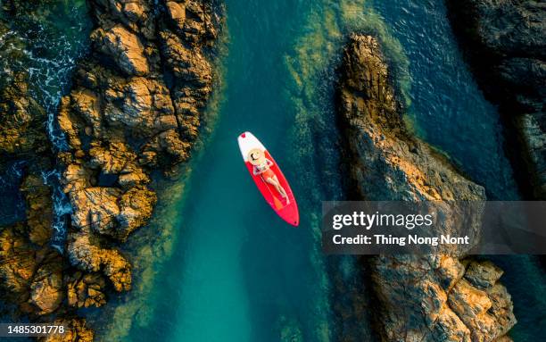 aerial view - attractive woman in bikini is sunbathing on a surfboard. thailand - white water rafting stock pictures, royalty-free photos & images