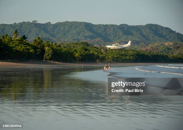 plane landing near tambor beach, nicoya peninsula, montezuma, costa rica - tambor stock pictures, royalty-free photos & images