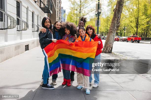 grupo de amigos posando con una bandera arcoíris antes del desfile del orgullo lgbtqia+ - desfile del orgullo gay fotografías e imágenes de stock