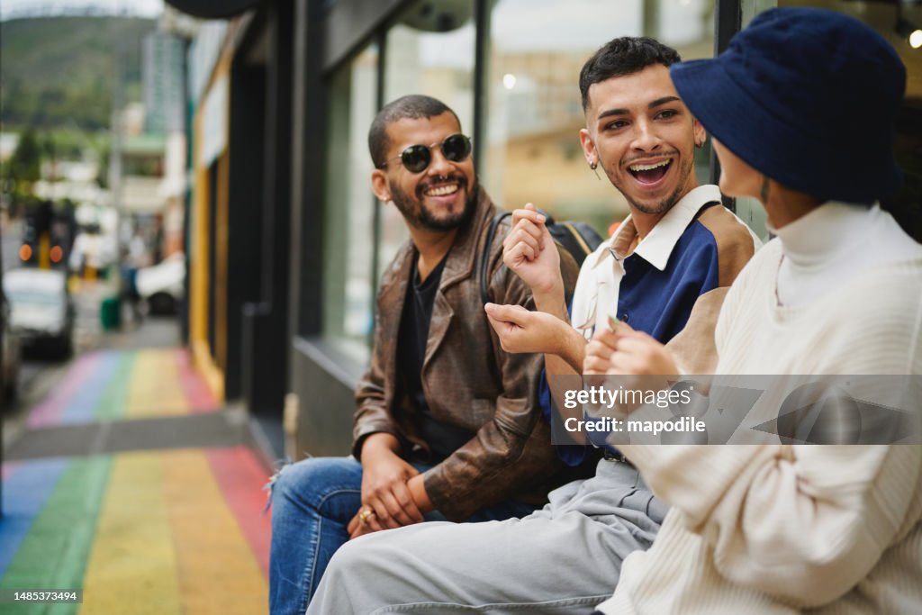 Freunde, die auf einem Bürgersteig reden und lachen, der in den Pride-Farben gestrichen ist