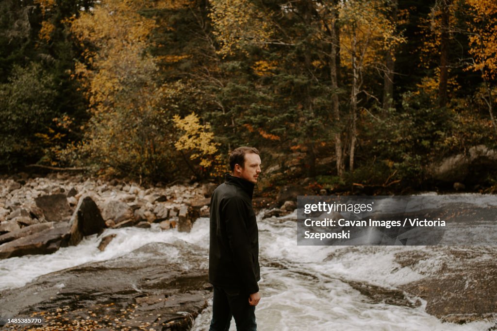 Young man hiking in nature on a cool fall day by a river
