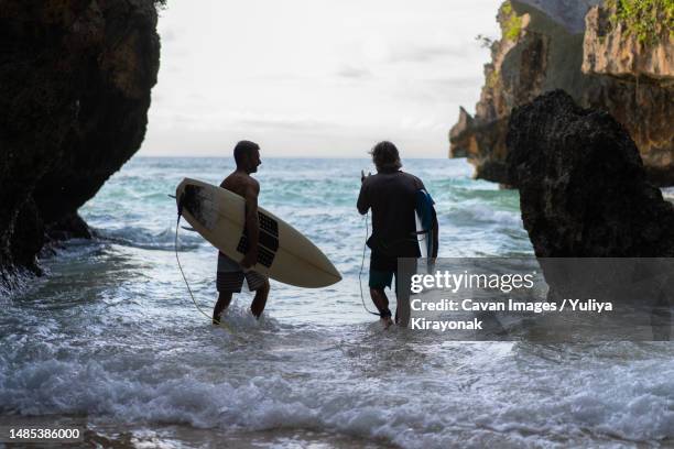 man with a surfboard goes to the uluwatu surf spot - uluwatu stock pictures, royalty-free photos & images