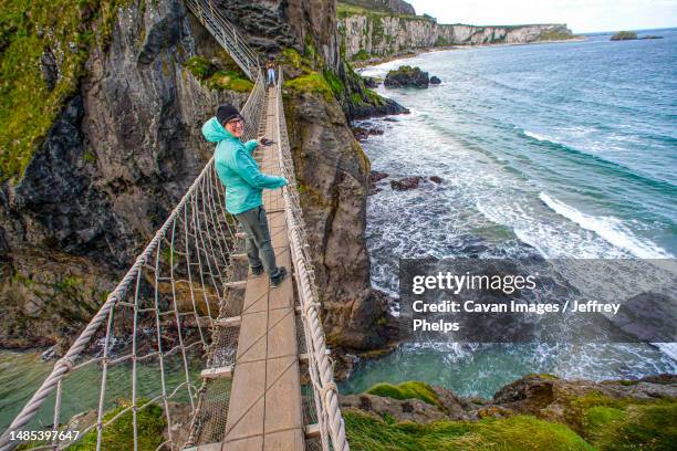 woman walks on bridge over water - hanging bridge stock pictures, royalty-free photos & images