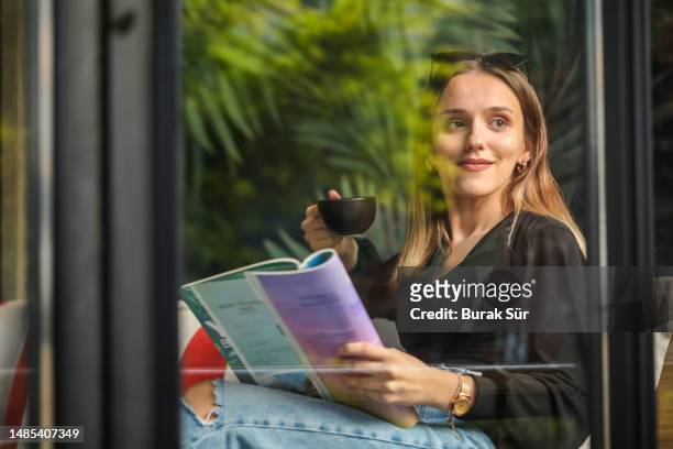giovane donna che legge una rivista, giovane donna d'affari che guarda fuori dalla finestra, stile di vita della donna - magazine foto e immagini stock