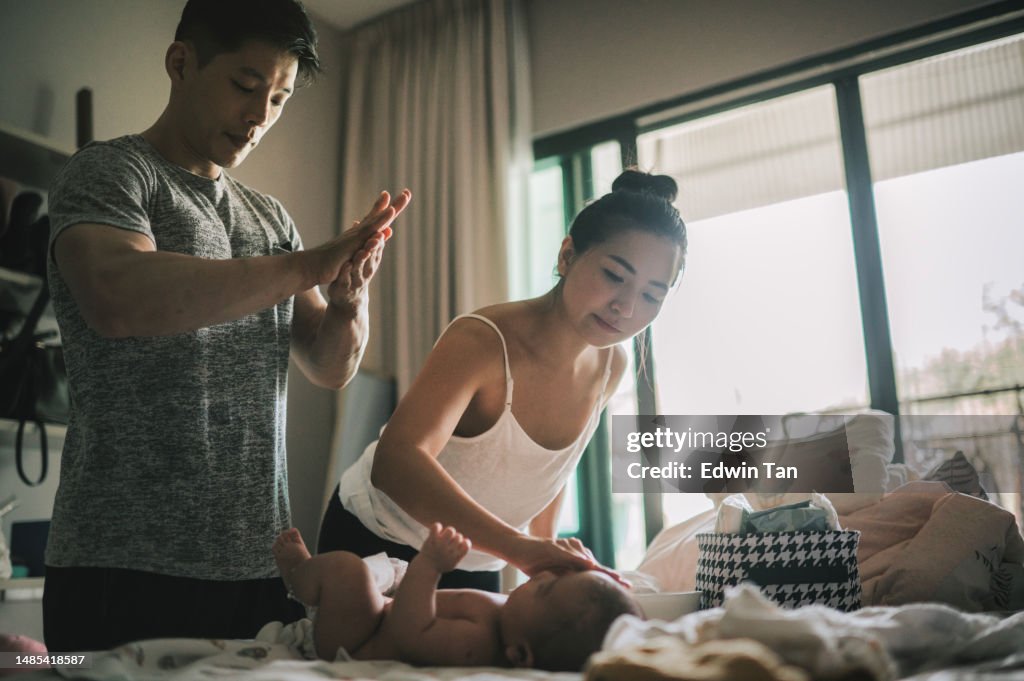 Asian Chinese parents applying lotion and changing baby clothing for their baby boy after bath