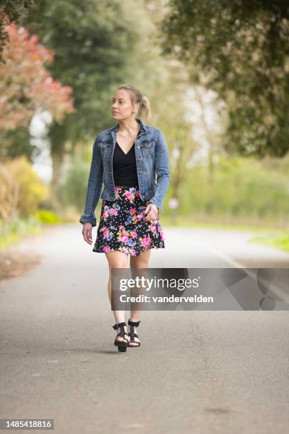 lady wearing a flowery skirt walking along a country road - sandal tree stock pictures, royalty-free photos & images