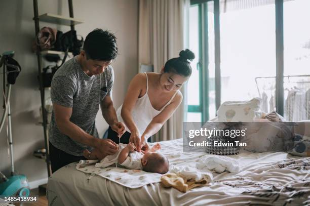 asian chinese parents applying lotion and changing baby clothing for their baby boy after bath - parental leave stock pictures, royalty-free photos & images