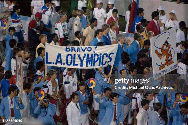 South Korean athletes wearing pale blue blazers, carry a banner reading 'Bravo LA Olympics' during the closing ceremony of the 1984 Summer Olympics,...
