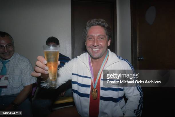 German weightlifter Rolf Milser enjoys a glass of beer following his gold-winning performance in the men's 100 kg competition of the men's...