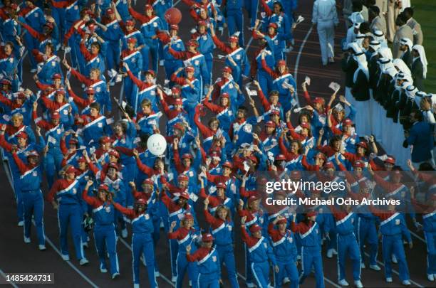 American athletes smiling and waving small American flags during the opening ceremony of the 1984 Summer Olympics, held at the Los Angeles Memorial...