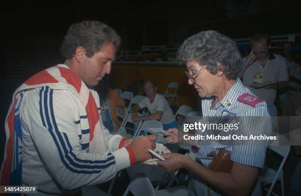 German weightlifter Rolf Milser signs an autograph for a female fan following his gold-winning performance in the men's 100 kg competition of the...