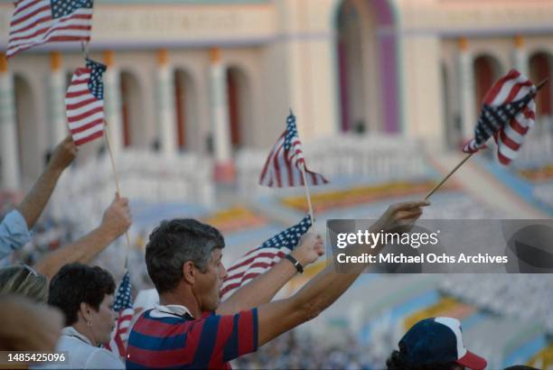 Spectators waving small American flags during the closing ceremony of the 1984 Summer Olympics, held at the Los Angeles Memorial Coliseum in Los...