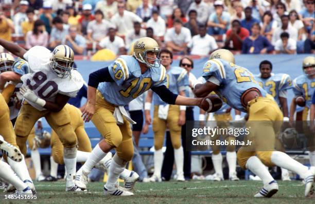 Rick Neuheisel hands off to running back during game action of UCLA Bruins against Washington Huskies, October 29, 1983 at Rose Bowl in Pasadena,...