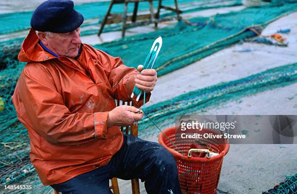 fisherman repairing fishing nets - union hall, county cork - fisherman stock pictures, royalty-free photos & images