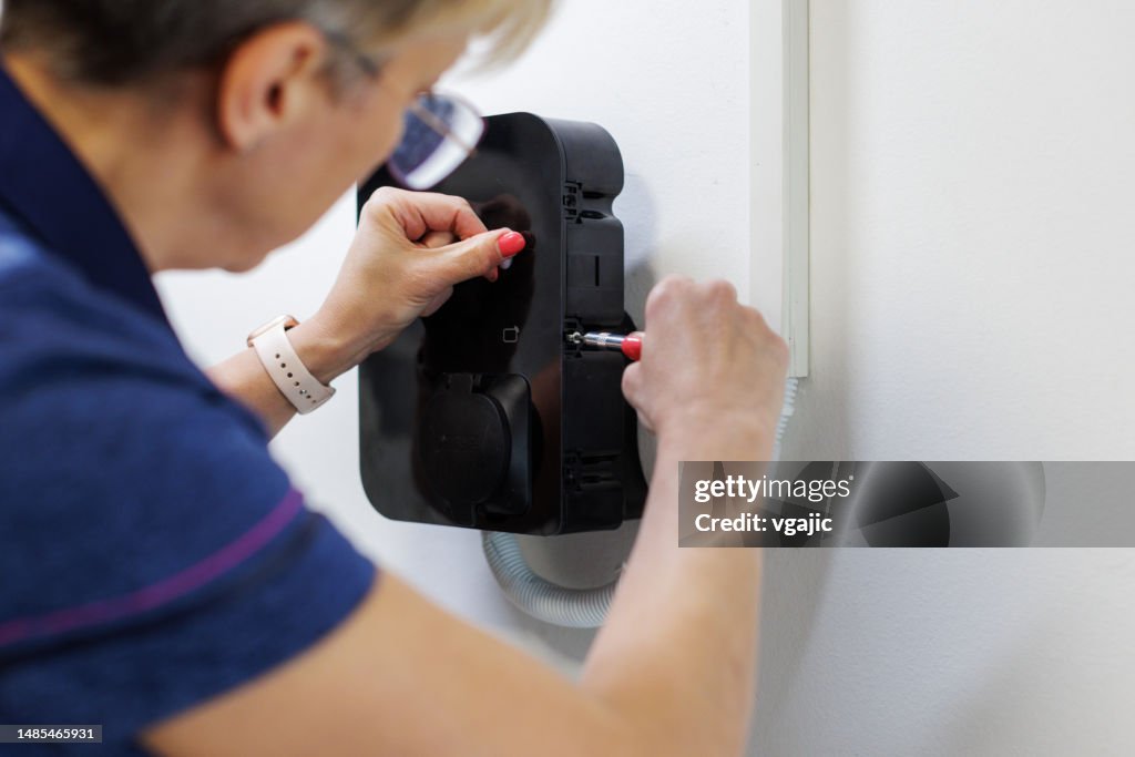 Female Electrician Finishing Installation Of Home EV Charger