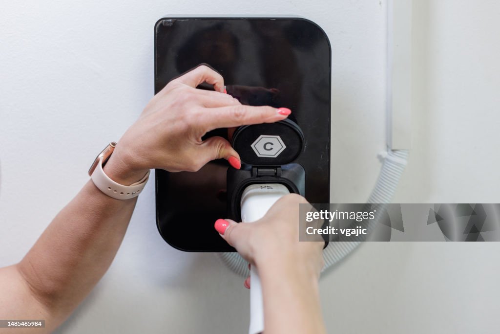 Woman Inserting Electric Cable Into Car Charger