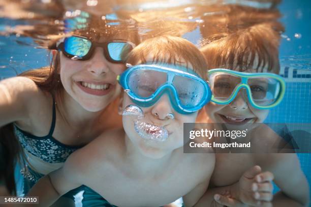 glückliche kinder spielen unter wasser - freibad stock-fotos und bilder