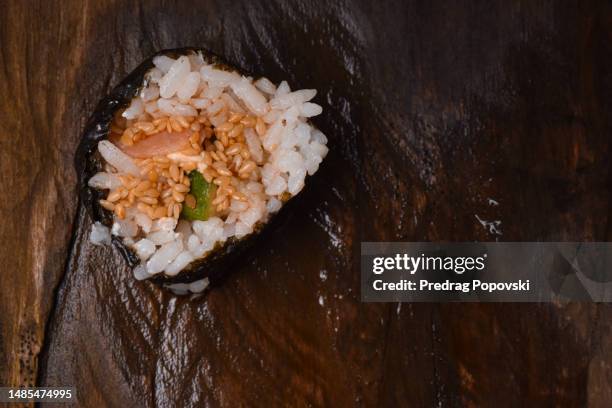 extreme closeup of sushi with chopsticks on wooden table with soy oil - hand roll stock pictures, royalty-free photos & images