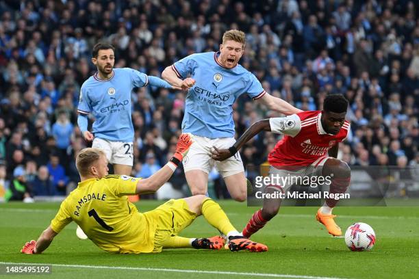 Kevin De Bruyne of Manchester City is challenged by Aaron Ramsdale and Thomas Partey of Arsenal during the Premier League match between Manchester...