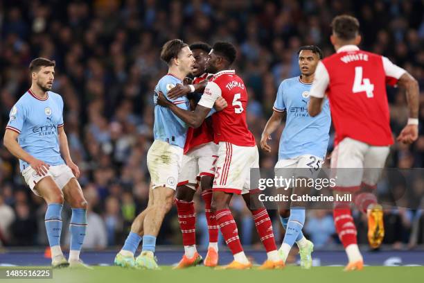 Jack Grealish of Manchester City clashes with Thomas Partey and Bukayo Saka of Arsenal during the Premier League match between Manchester City and...