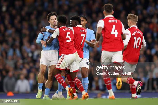 Jack Grealish of Manchester City clashes with Thomas Partey and Bukayo Saka of Arsenal during the Premier League match between Manchester City and...