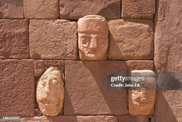 wall with sculpted heads at subterranean temple. - ruïnes van tiahuanaco stockfoto's en -beelden