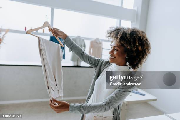 woman checking quality of pants in clothing store - tailor pants stock pictures, royalty-free photos & images