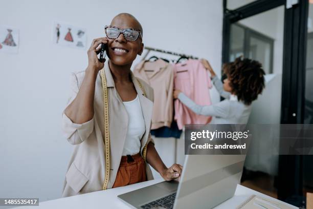 clothing store manager talking on smartphone - clothing store stockfoto's en -beelden