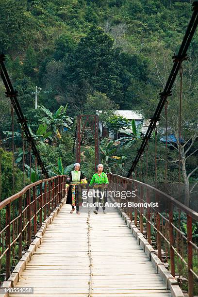 two hmong women crossing bridge. - bao lac stock pictures, royalty-free photos & images