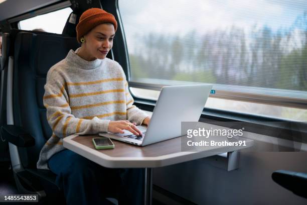 beautiful young woman working on laptop in train - public transportation stockfoto's en -beelden