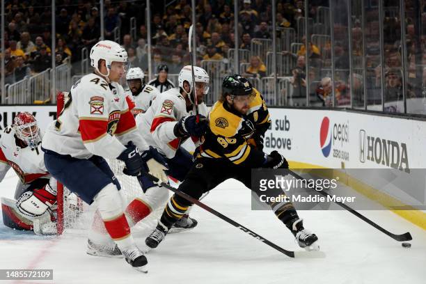 David Pastrnak of the Boston Bruins battles for the puck against Gustav Forsling and Aaron Ekblad of the Florida Panthers during the first period in...
