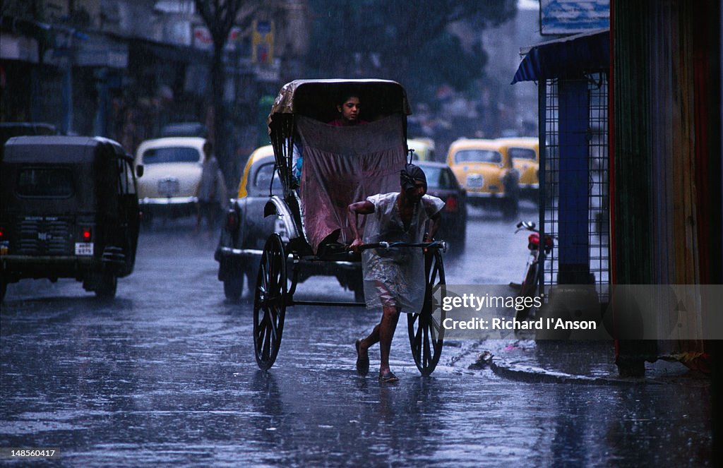 A soaked rickshaw puller gets a passenger home safe and dry during the monsoons of Calcutta