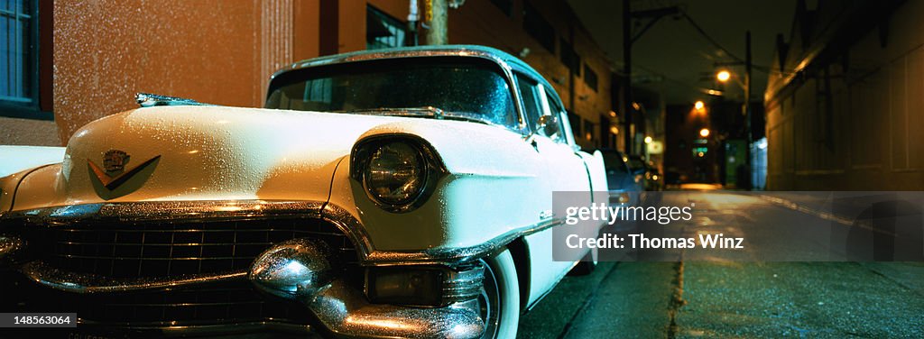 Cadillac (1952) parked in alley at night.