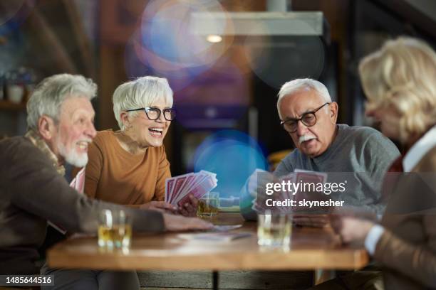 group of happy seniors having fun while playing cards at home. - retirement card stock pictures, royalty-free photos & images