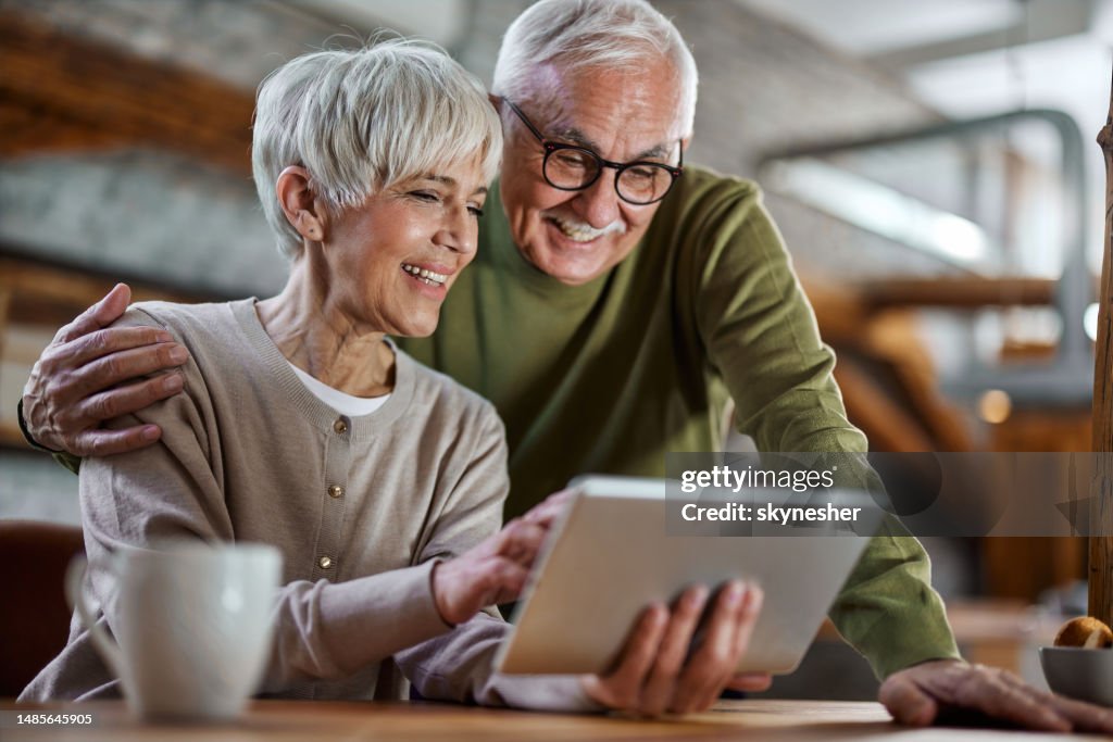 Glückliches reifes Paar, das es genießt, ein digitales Tablet zu Hause zu verwenden.