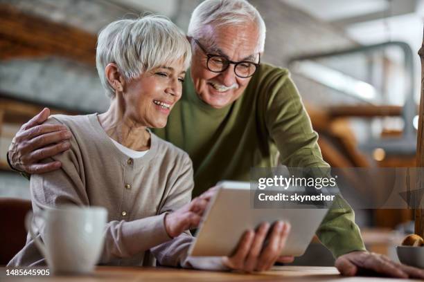 glückliches reifes paar, das es genießt, ein digitales tablet zu hause zu verwenden. - couple tablet house stock-fotos und bilder