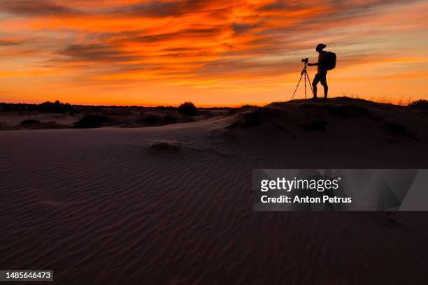 photographer on a sand dune in the desert at sunset. - photographing sunset stock pictures, royalty-free photos & images
