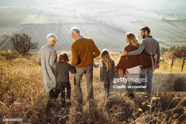 rückblick auf glückliche großfamilie, die am herbsttag den hügel hinunterzieht. - familie mit mehreren generationen stock-fotos und bilder