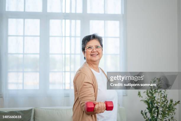 strong senior woman exercising with dumbbells in his home - hand weight stock pictures, royalty-free photos & images