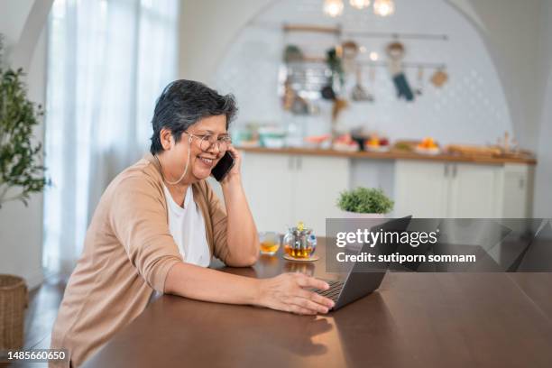 asian senior woman using the laptop and talking mobile phone smiling happiness - comminuted fracture stock pictures, royalty-free photos & images